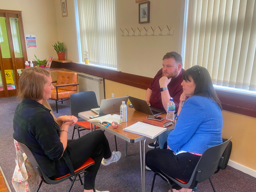 Cllr Cal Johnston-Dempsey and Stephanie Callaghan MSP sitting at a table with a constituent, discussing a case.